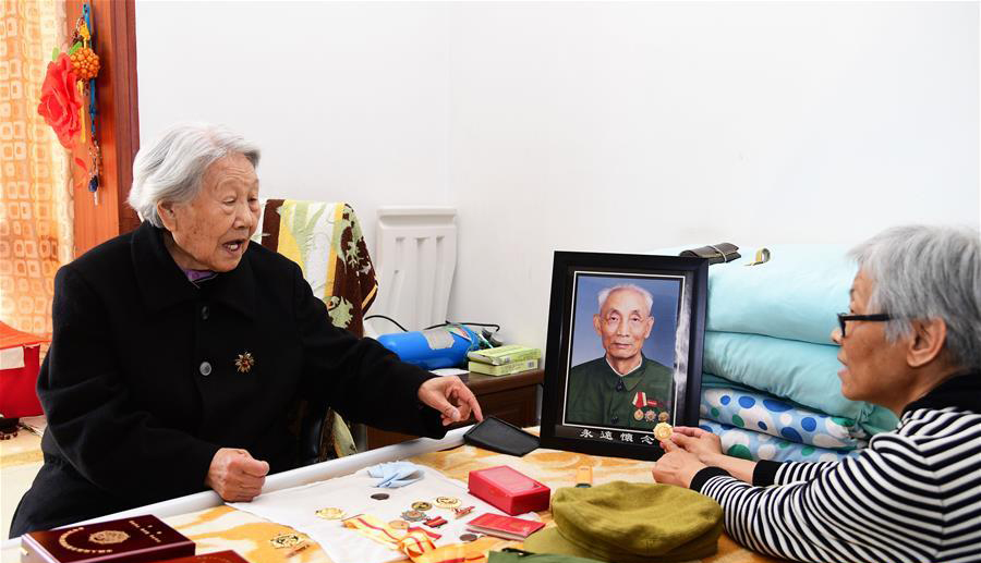 娄淑珍(左)与女儿一起整理周智夫获得的荣誉章(2018年4月8日摄)。