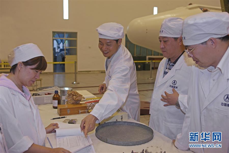 在西昌卫星发射中心总装车间,长三甲系列运载火箭总指挥岑拯(左二)在和科研人员交流(2009年8月11日摄)。新华社发(航天科技集团第一研究院供图)