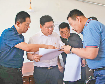 杨勇（左二）在乡镇检查指导脱贫攻坚工作。资料照片