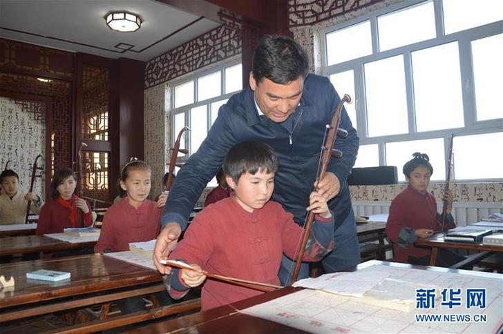 库尔班·尼亚孜辅导学生拉二胡（资料照片）。