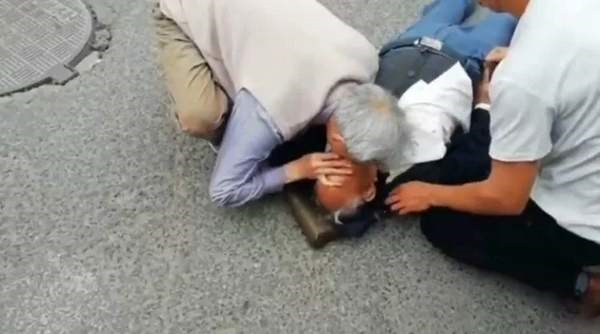 图为于守堤老人跪地给病人进行人工呼吸急救