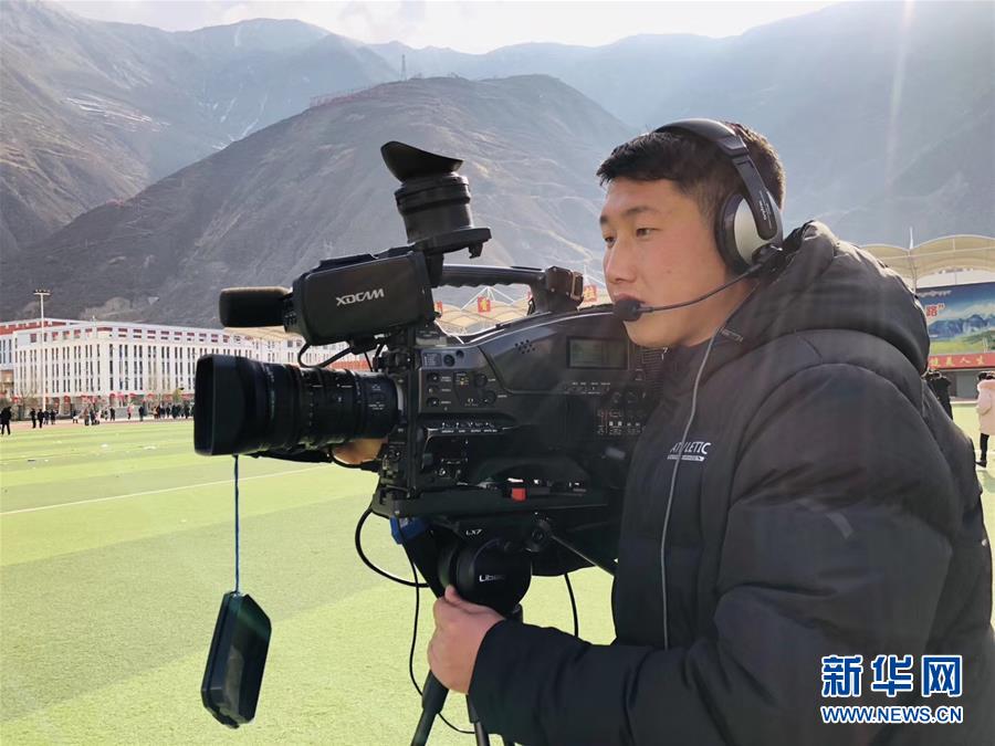 闵江伟在2019年舟曲县春节民俗文化活动现场参加现场直播(2019年2月14日摄)。新华社发